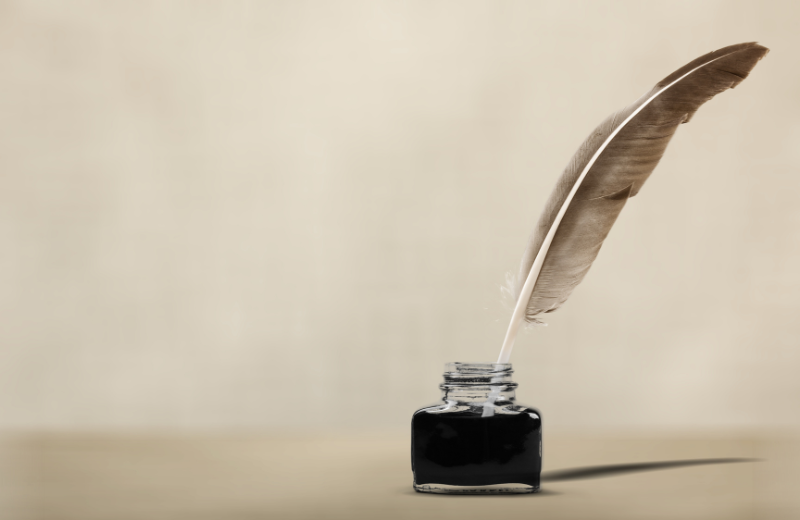 feather quill dipped into ink pot