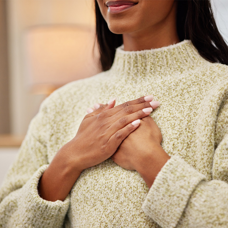 Closeup of a woman holding her chest in a pose of self-compassion