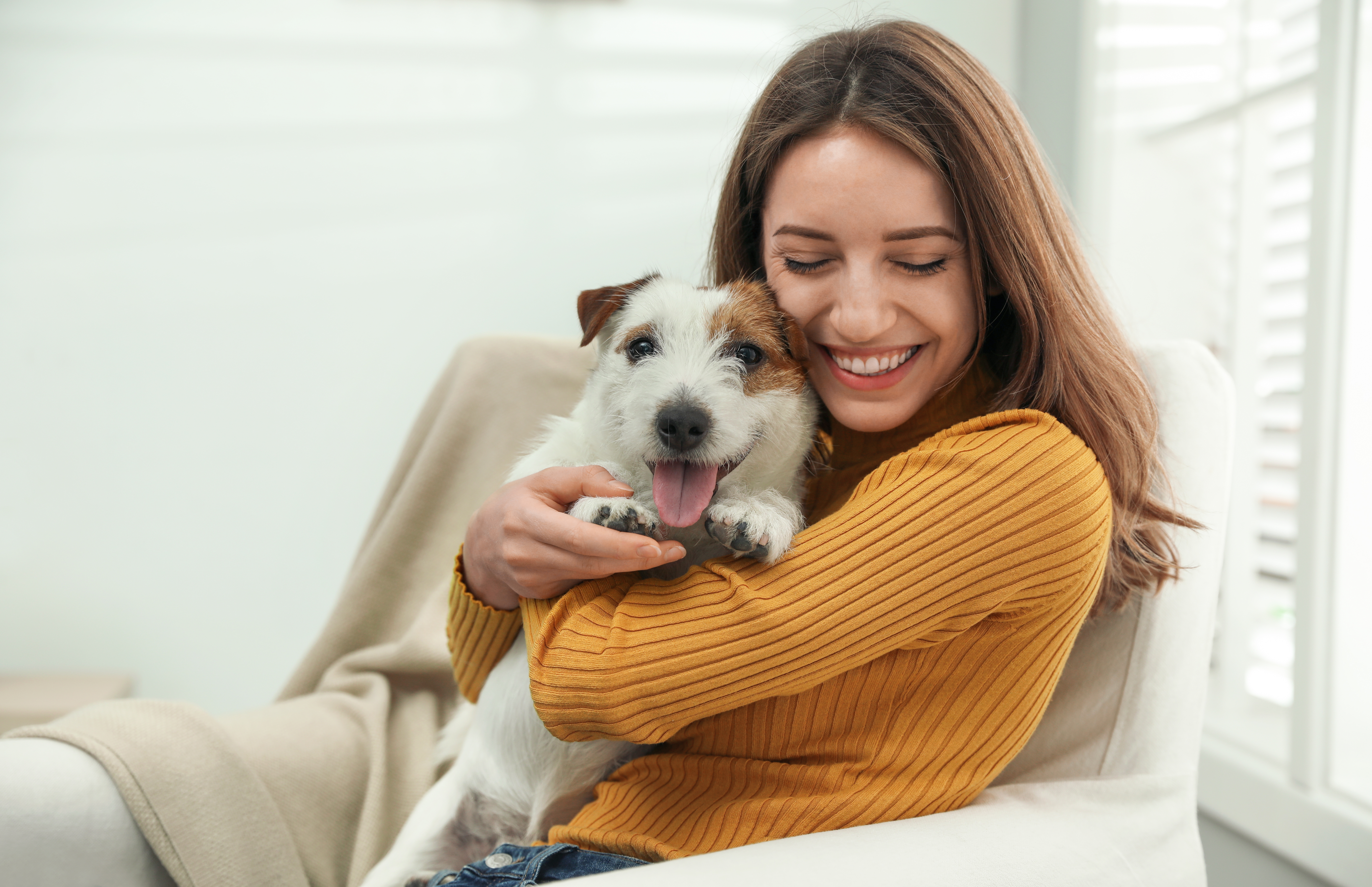 Woman in mustard sweater hugging dog