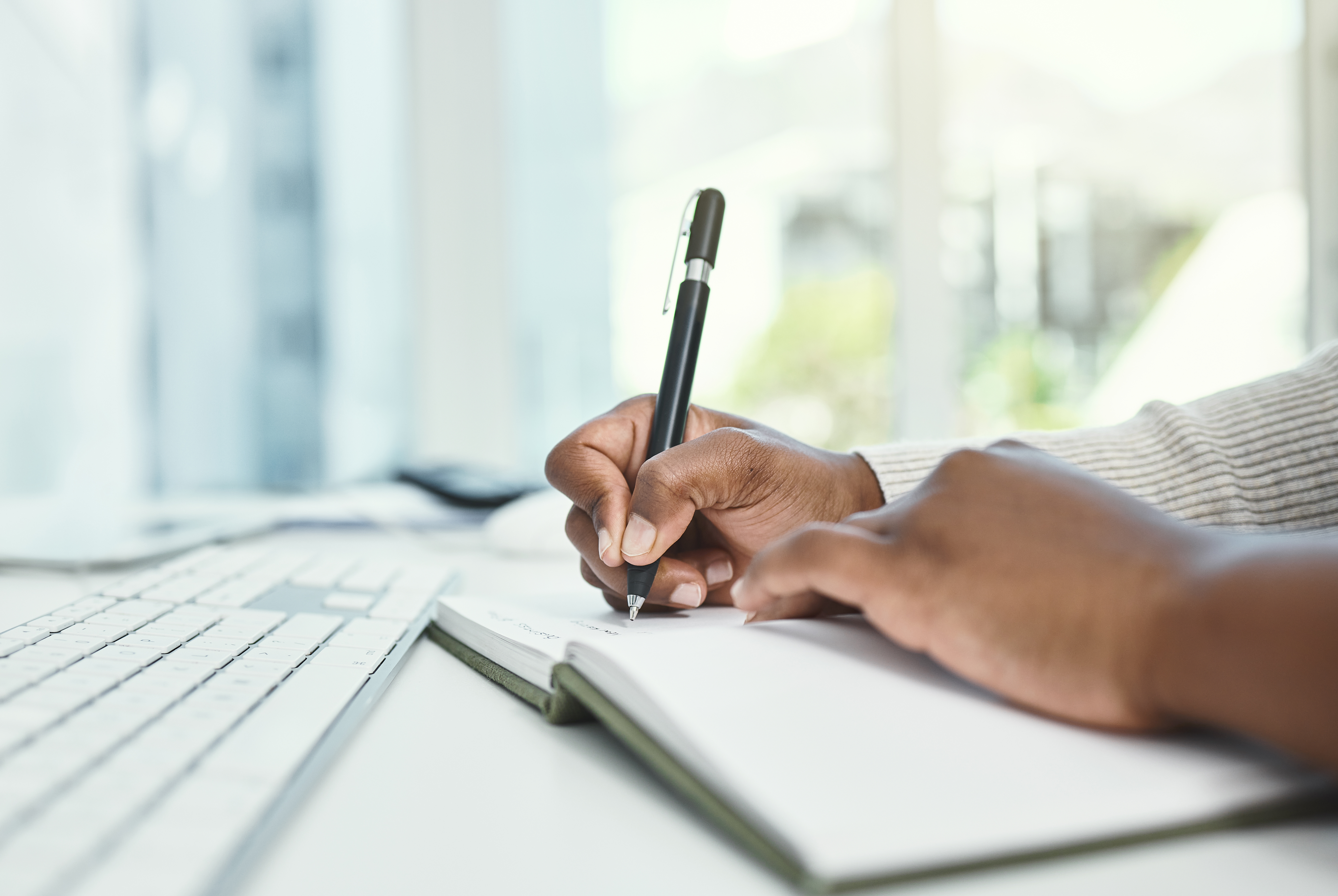 Person writing in a notebook with white background