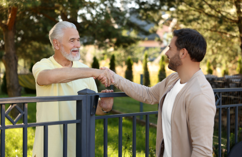 neighbours shaking hands over the fence