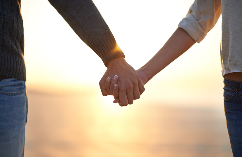 Image of two people holding hands.