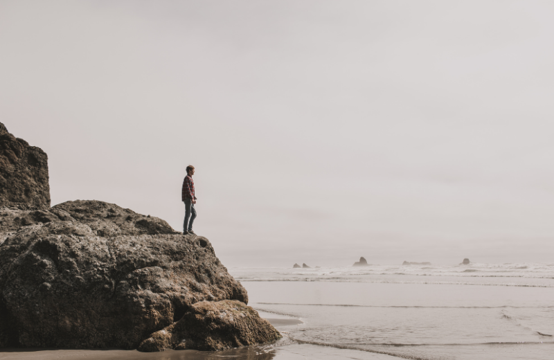man standing alone on cliff above stormy sea
