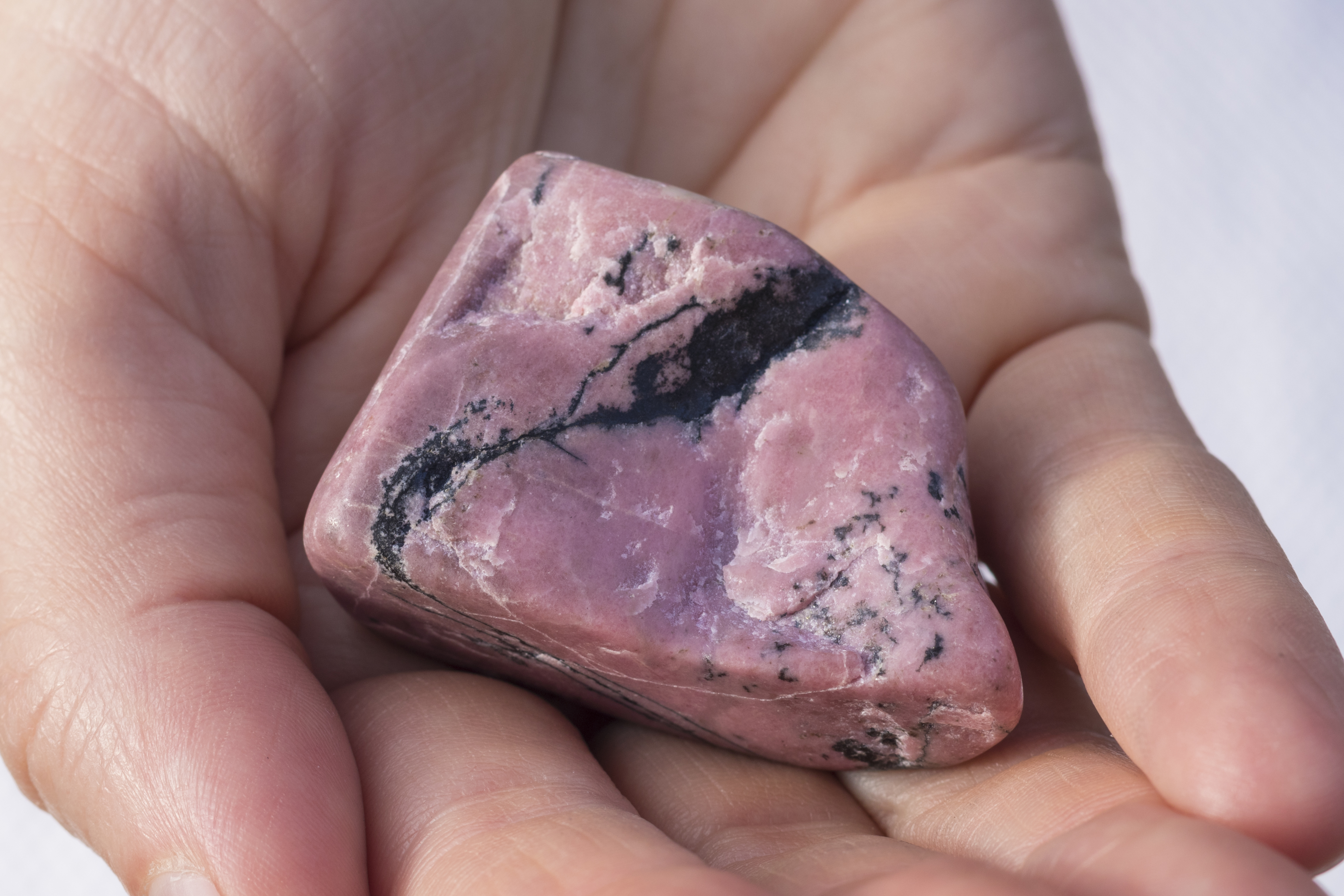 A piece of Rhodonite in the palm of a hand