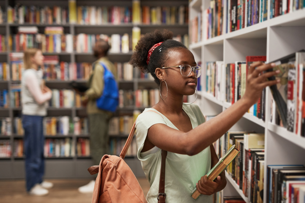 A young woman picking out a book from a library