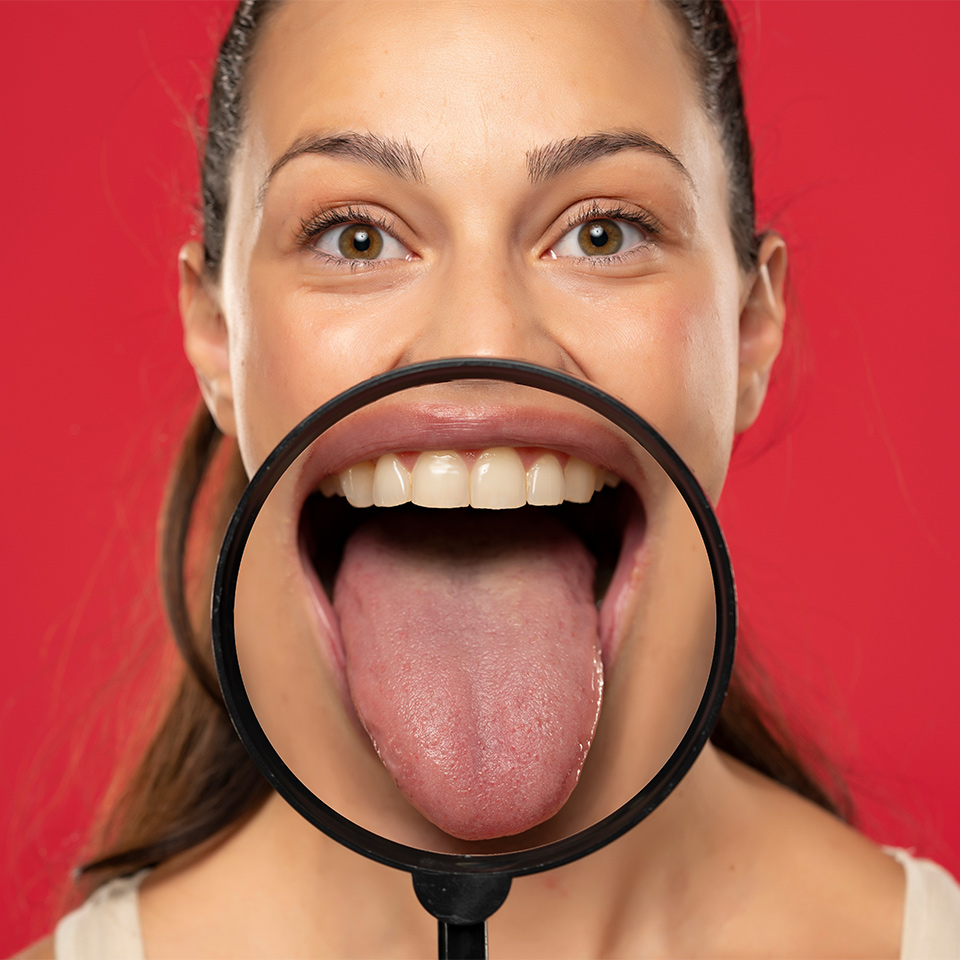 Person showing their tongue through a magnifying glass