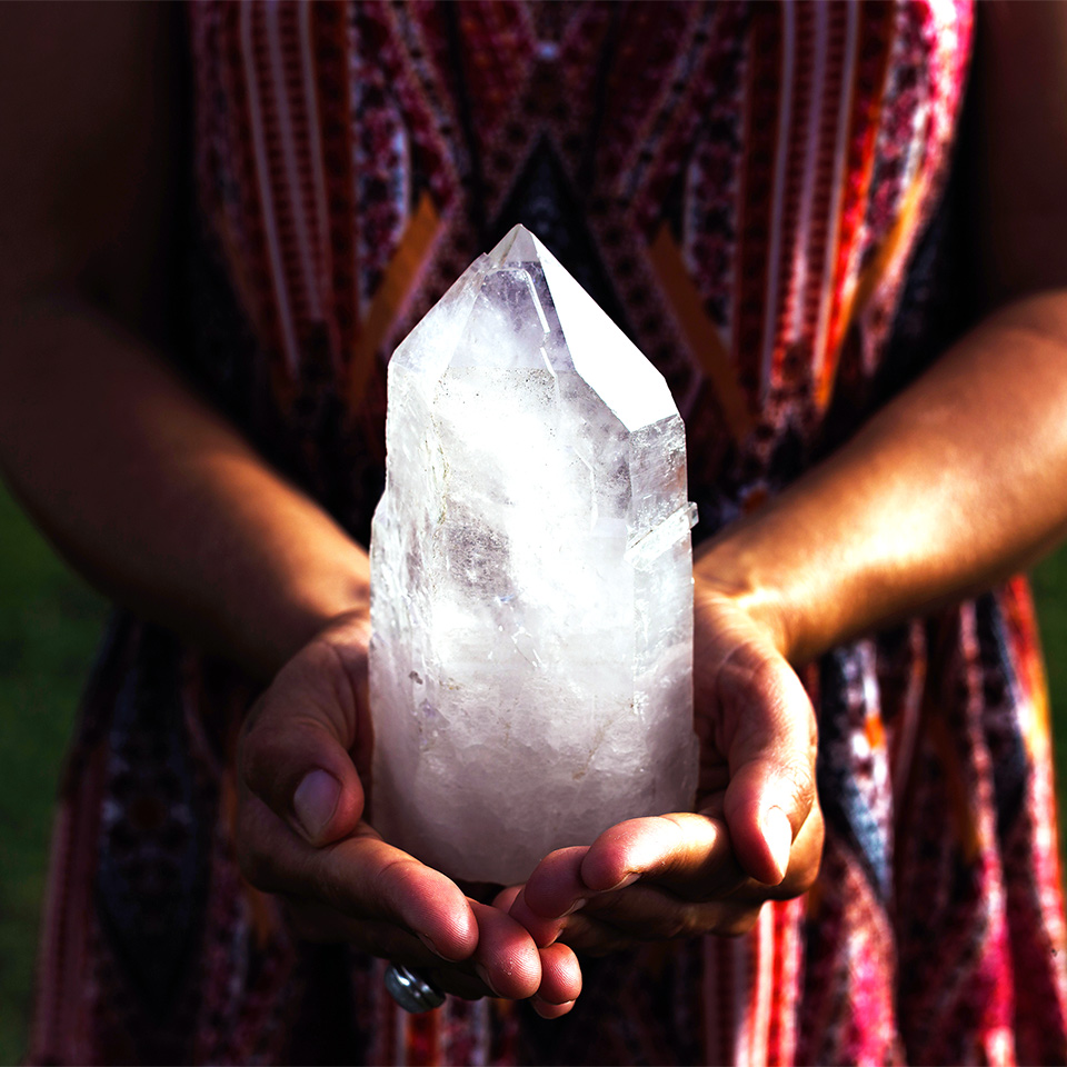 A woman holding a large, luminous quartz crystal