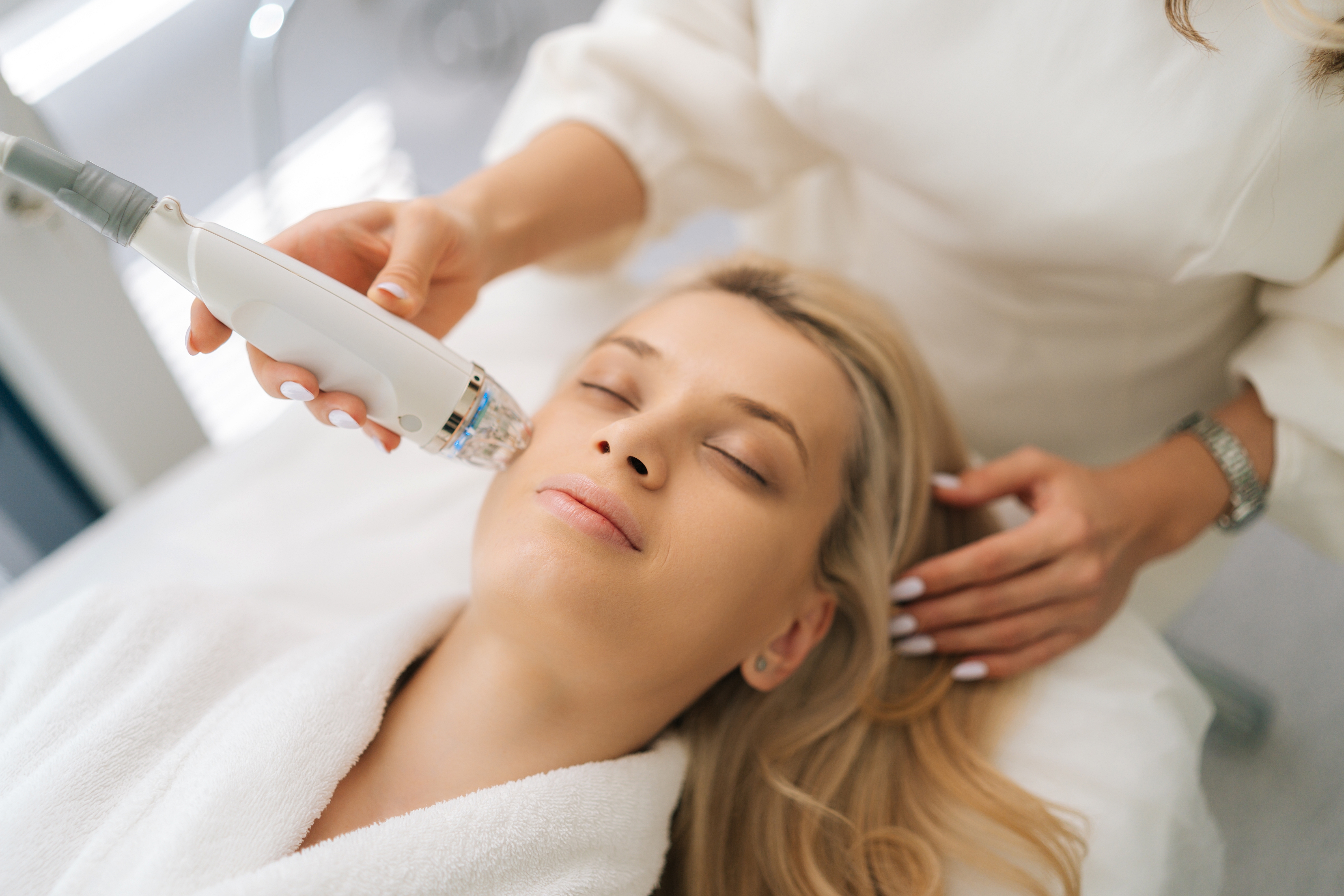 Beauty therapist working on woman's skin