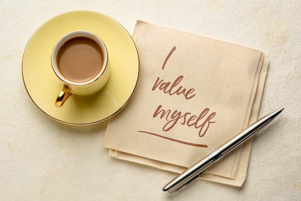 'I value myself' written on a napkin next to a coffee