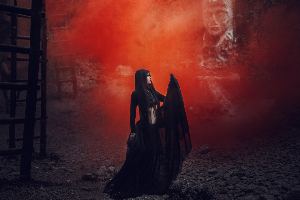 A woman dressed all in black with red mist behind