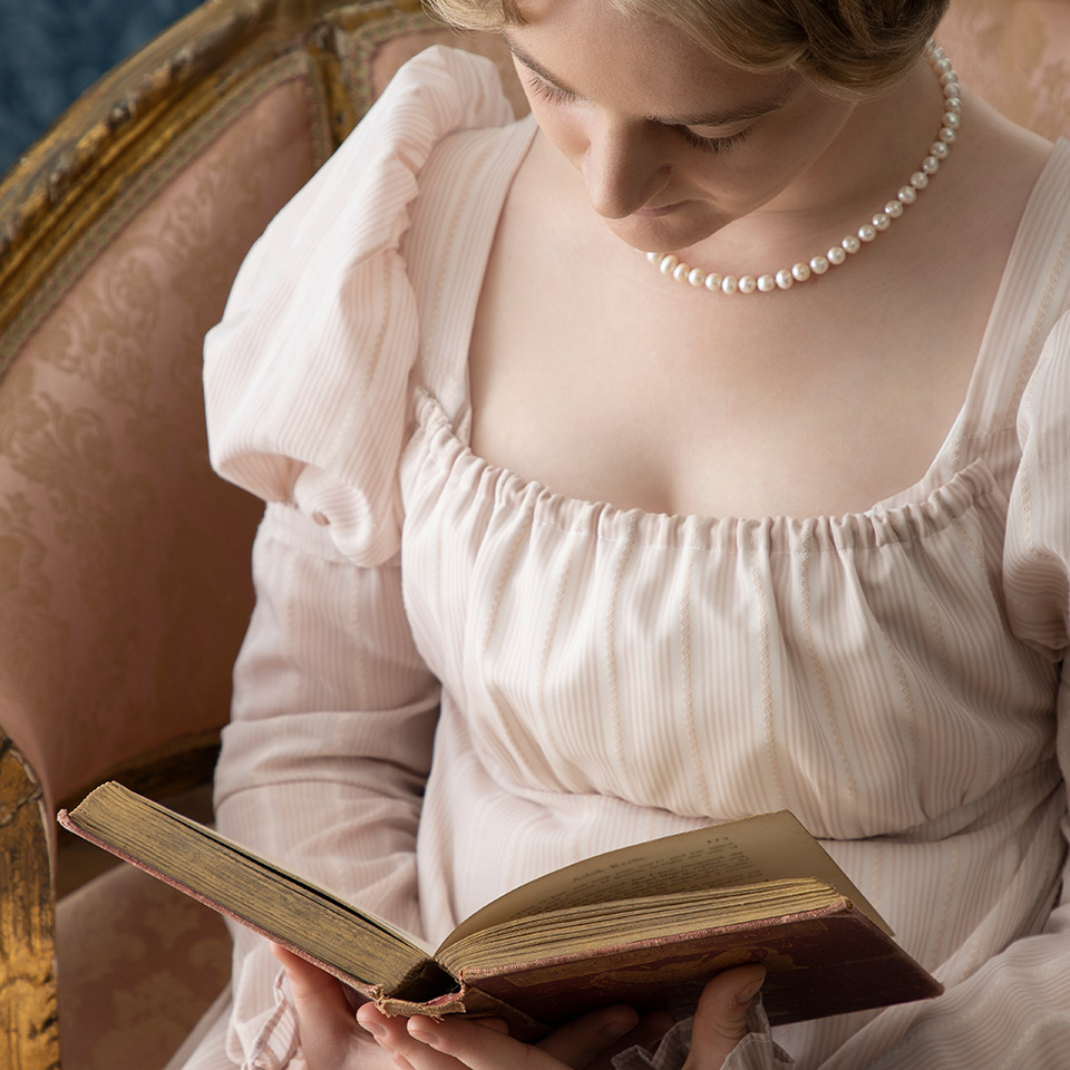 A young Regency woman in a pink dress in a Regency room