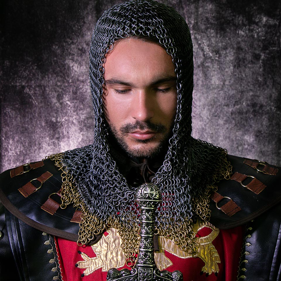Knight in suit of armour with beard and sword, looking down in contemplation