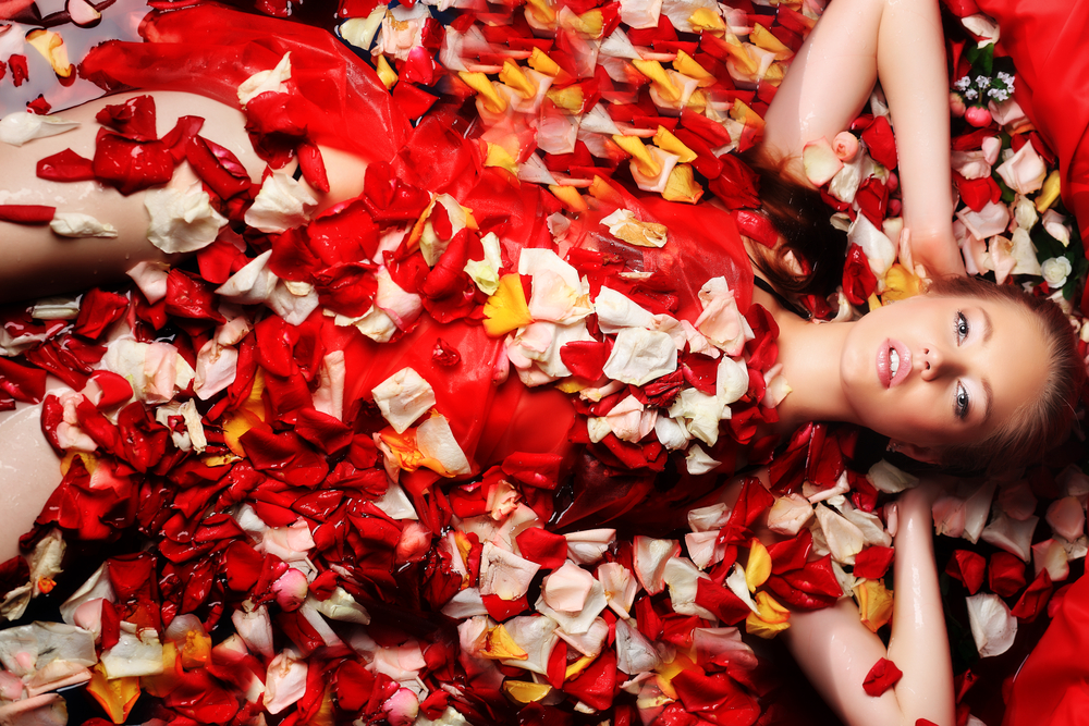 Woman lying in and surrounded by rose petals