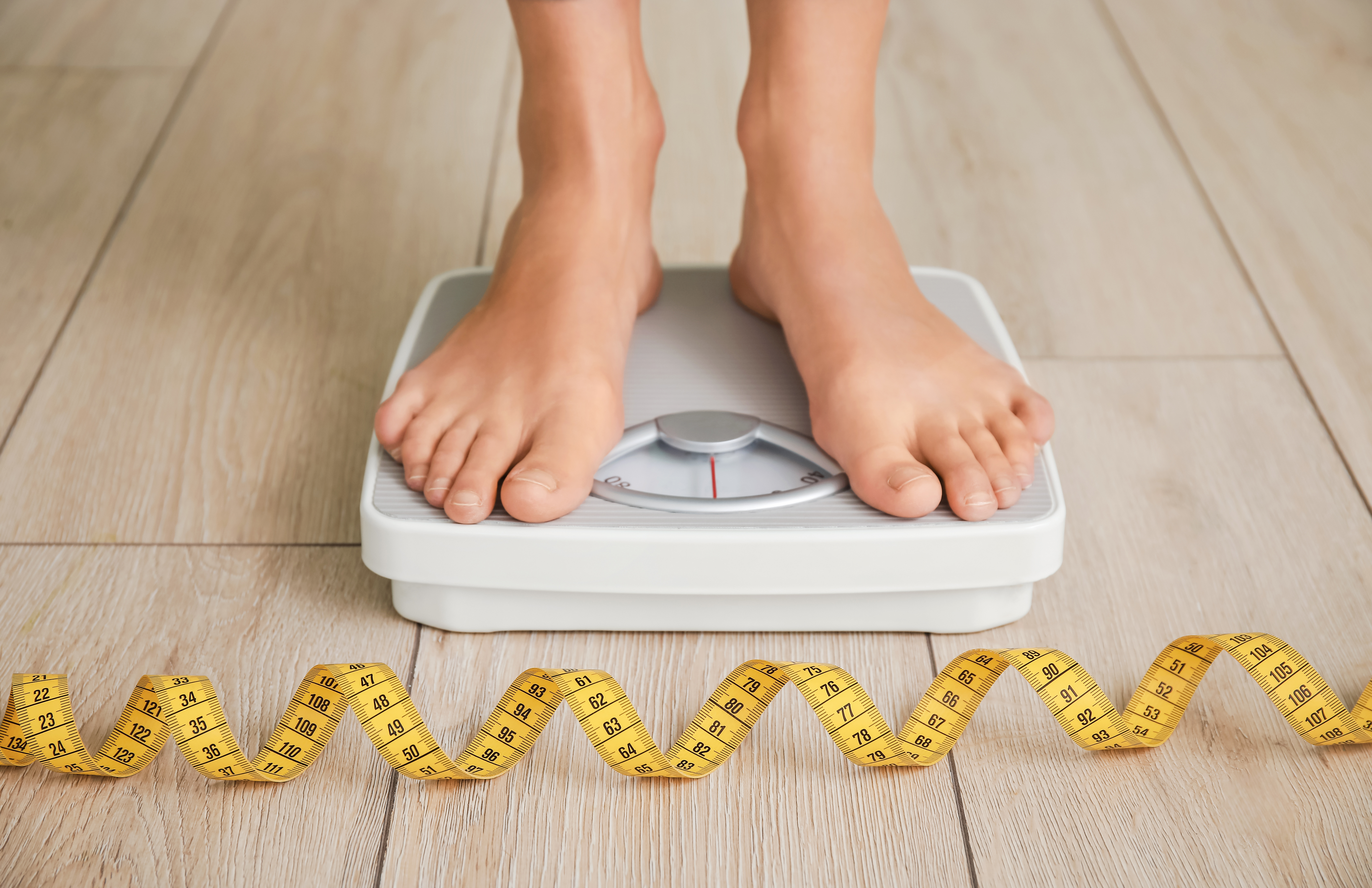 Weight loss person standing on scales feet