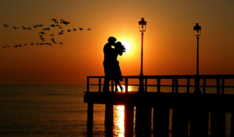 romantic couple on pier at sunset