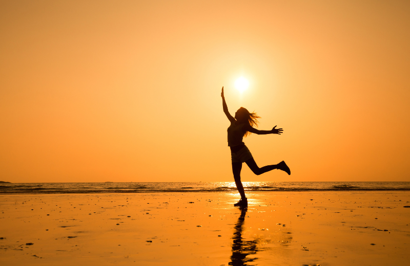 woman dancing on the beach at sunset