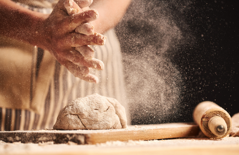 person rolling out sourdough with flour