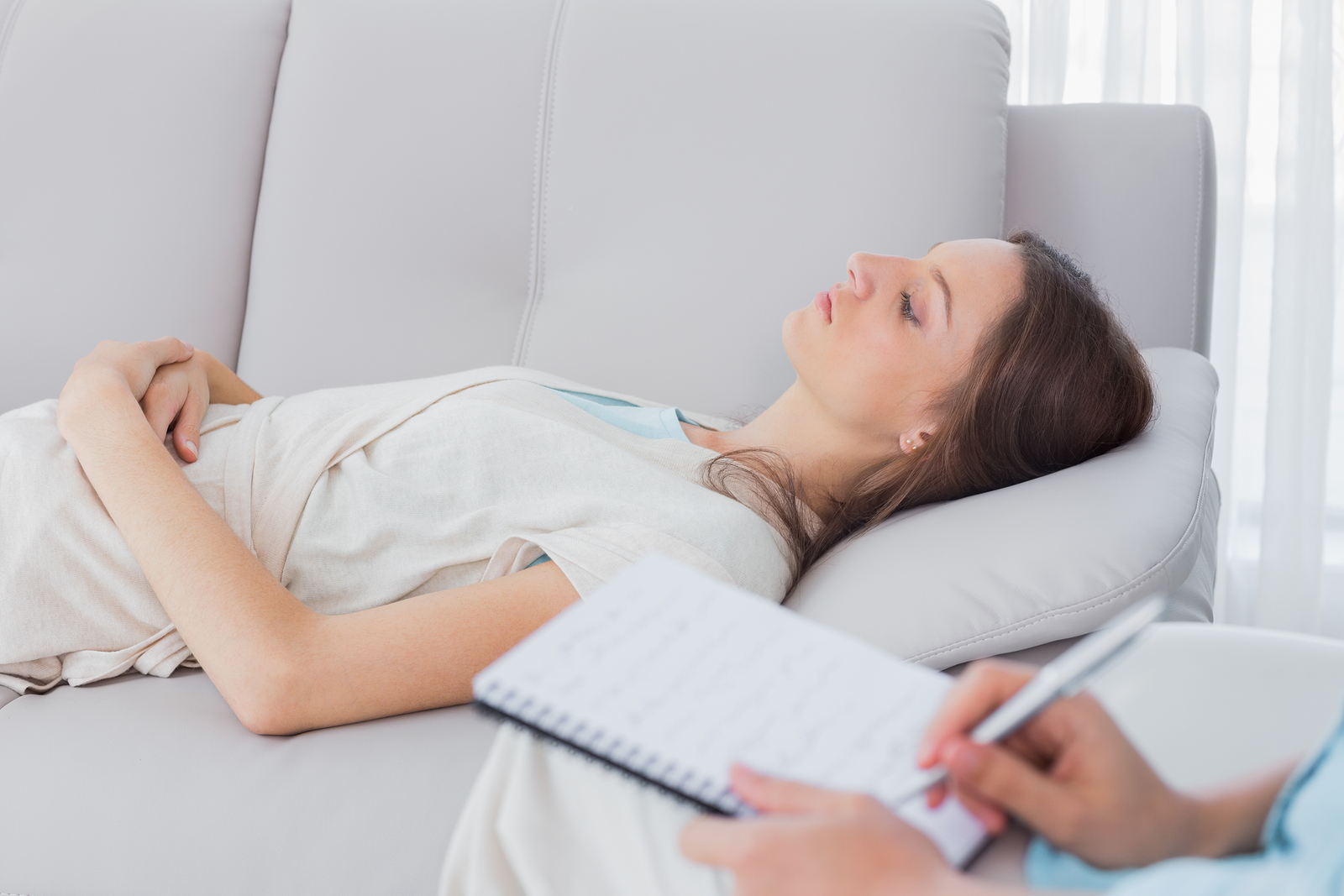 A woman lying on a sofa undergoing hypnotherapy
