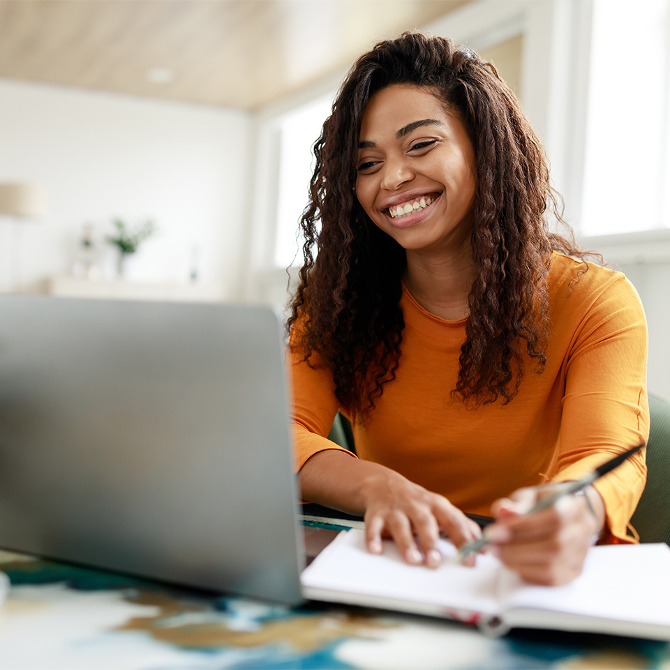 Smiling person doing beginner maths for adults at a laptop