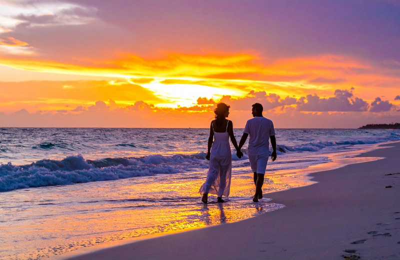 couple walking on beach at sunset