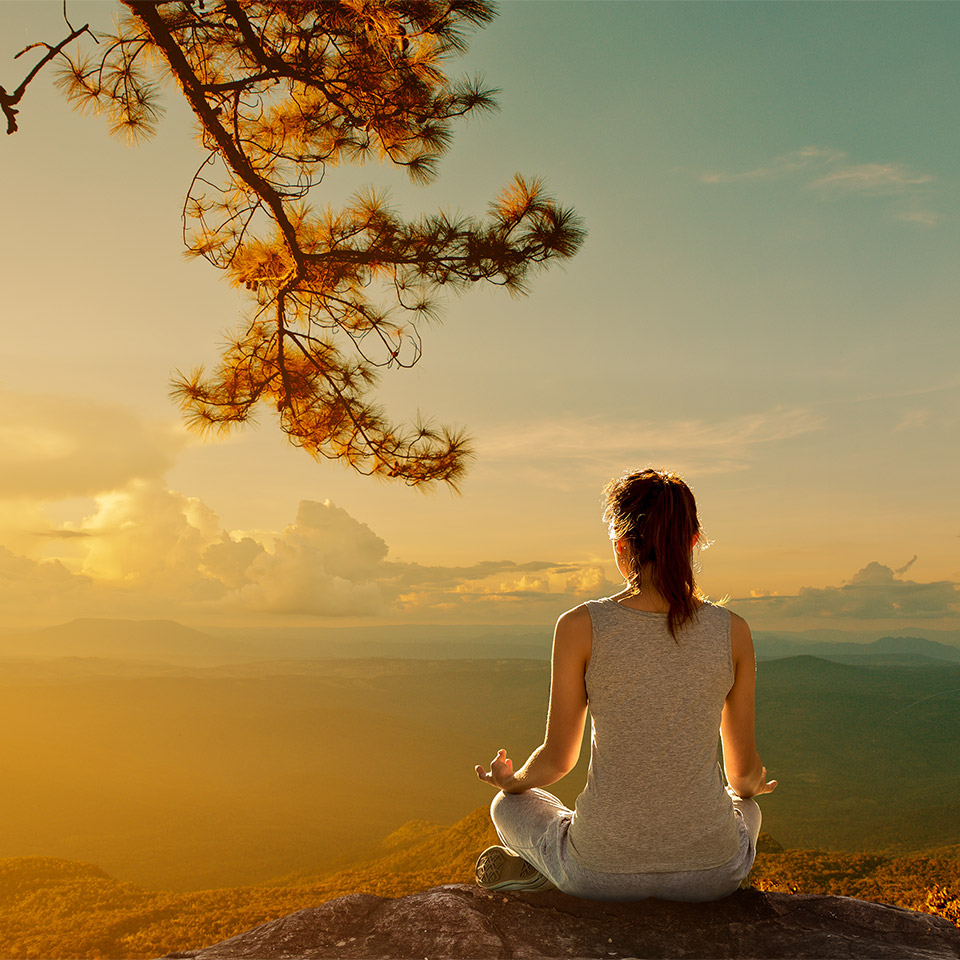Silhouette of a person holding a meditation pose on a mountain.