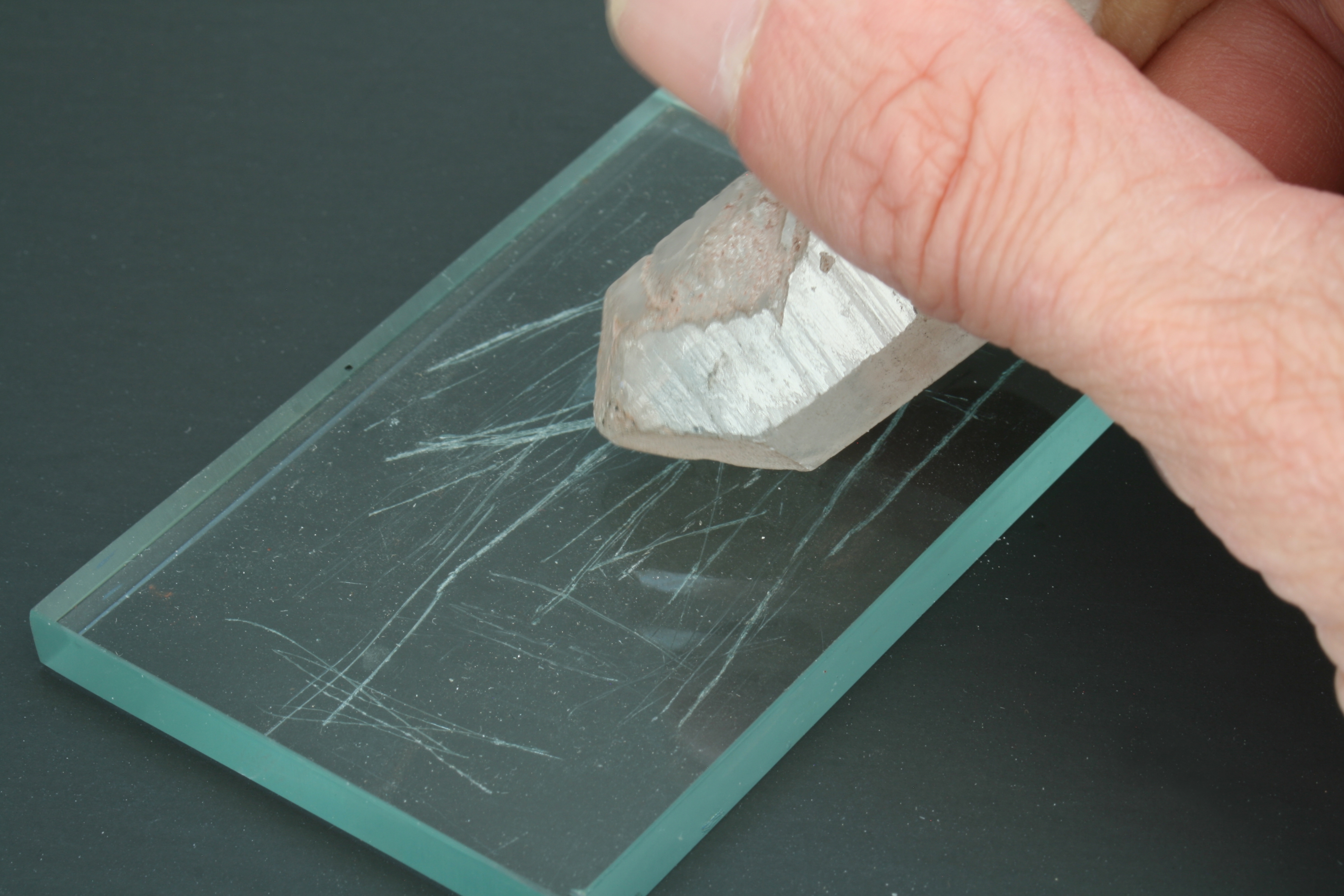 A crystal scratching a piece of glass