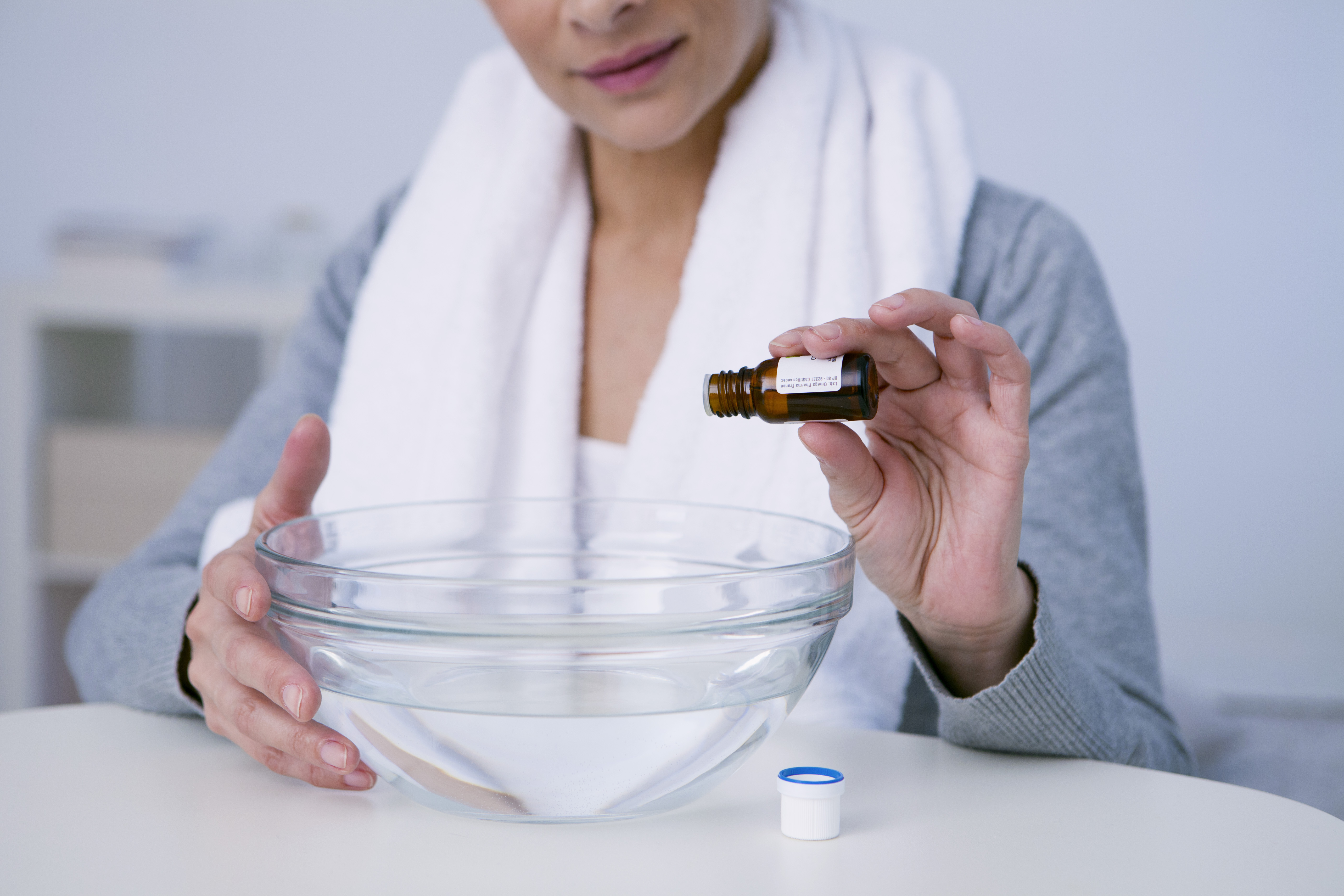 Person dropping essential oils into a bowl for steam inhillation