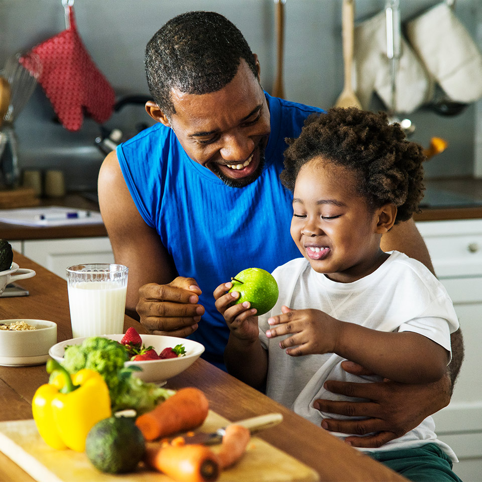 A father and son in their kitchen enjoying healthy fruit and vegetables