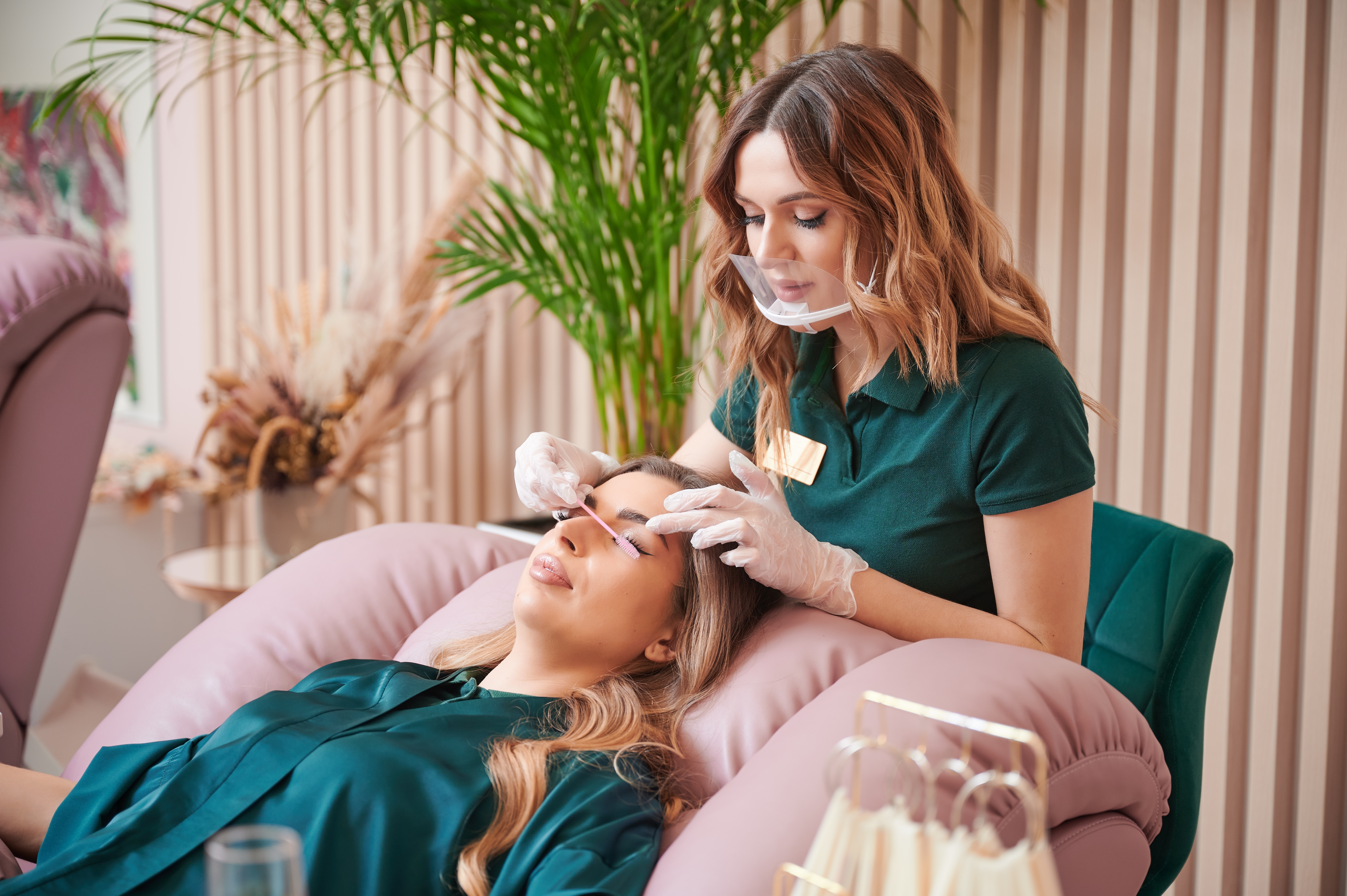 Lash technician combing a woman's lashes