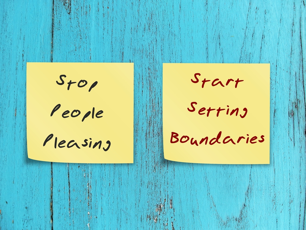 Two sticky notes, one says 'stop people pleasing' and one says 'start setting boundaries'