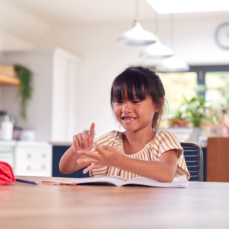 Young girl working at table at home, counting on her fingers