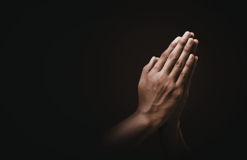 praying hands in dark room