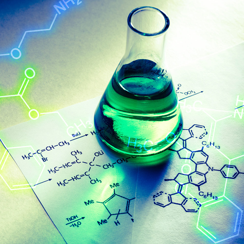 Beaker of a liquid on top of a piece of paper showing the structural formula of a chemical compound