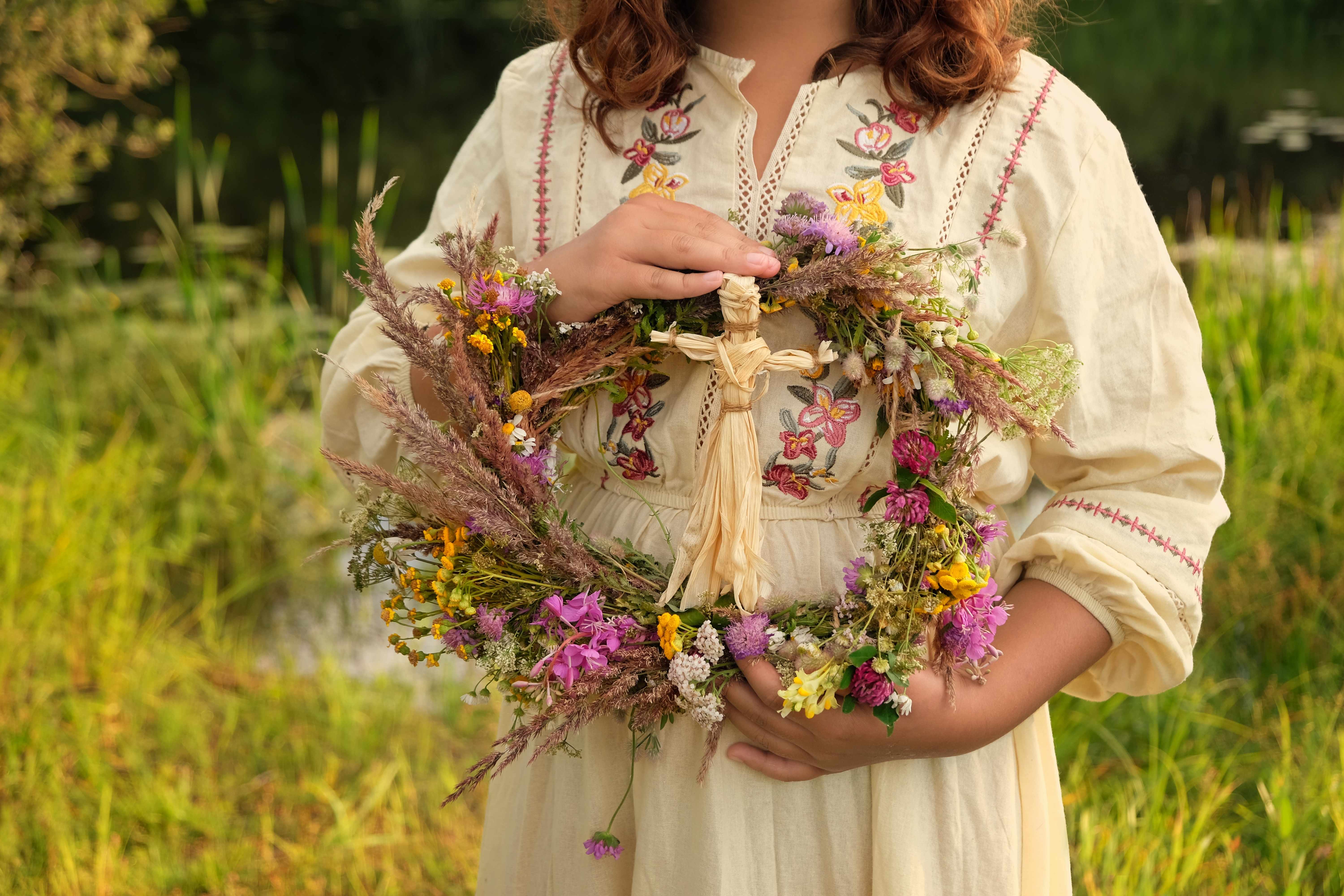 Someone holding a wreath of flowers with a figure in the middle