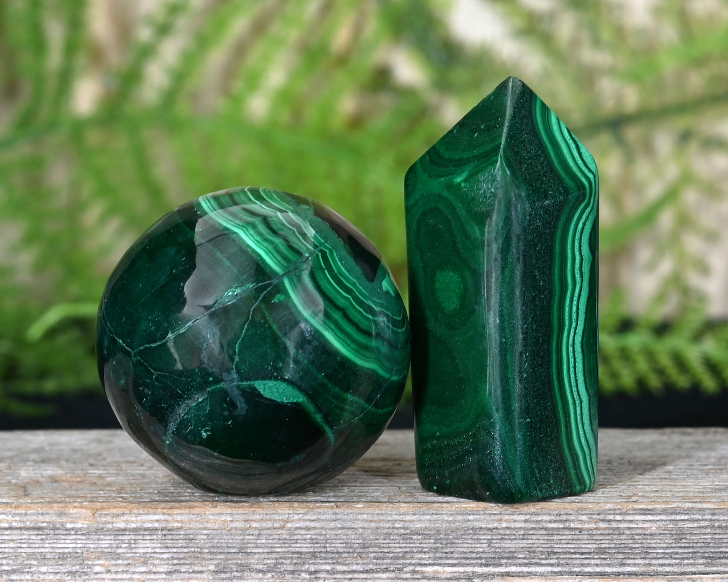 A round piece of Malachite next to a pointed piece of Malachite