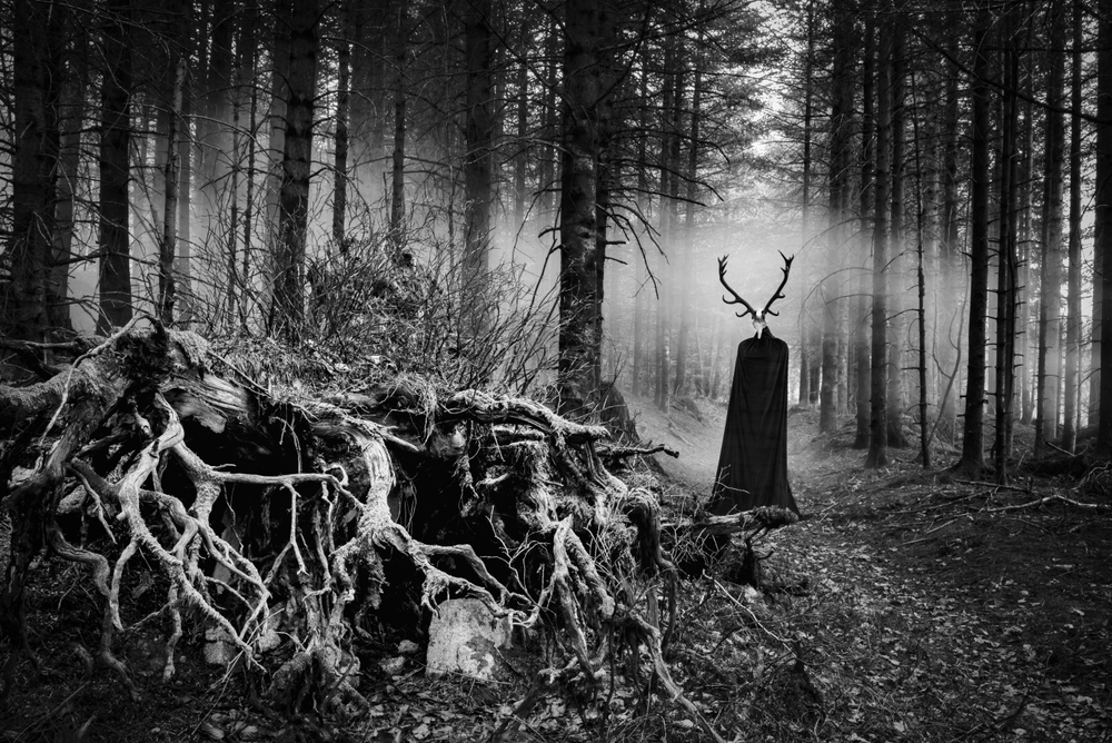A dark figure with deer antlers in a forest