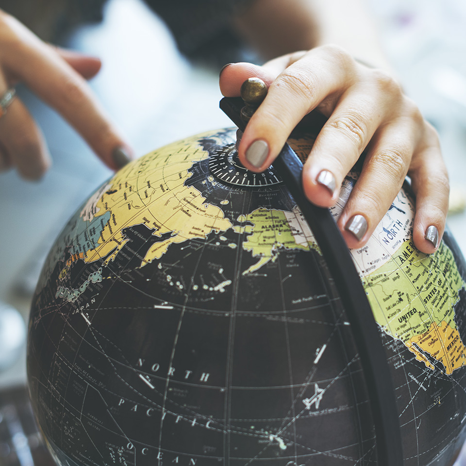 Hand pointing to a location on a globe