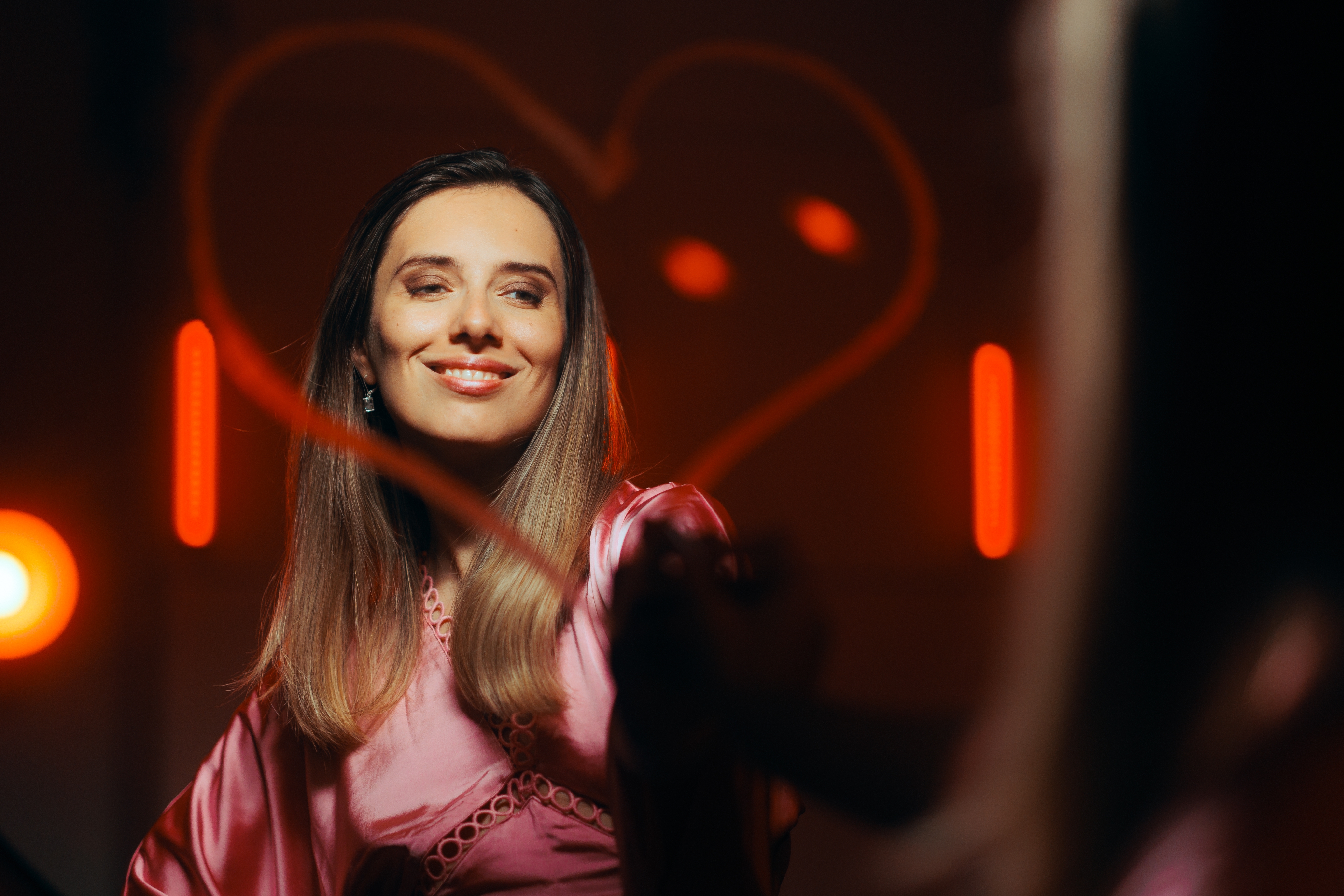 A woman smiling at her reflection in the mirror that she has drawn a heart around