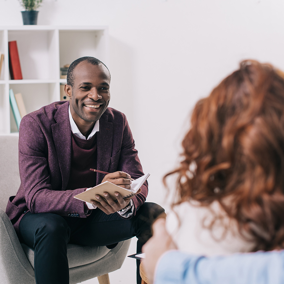 Smiling psychiatrist talking to a young person.
