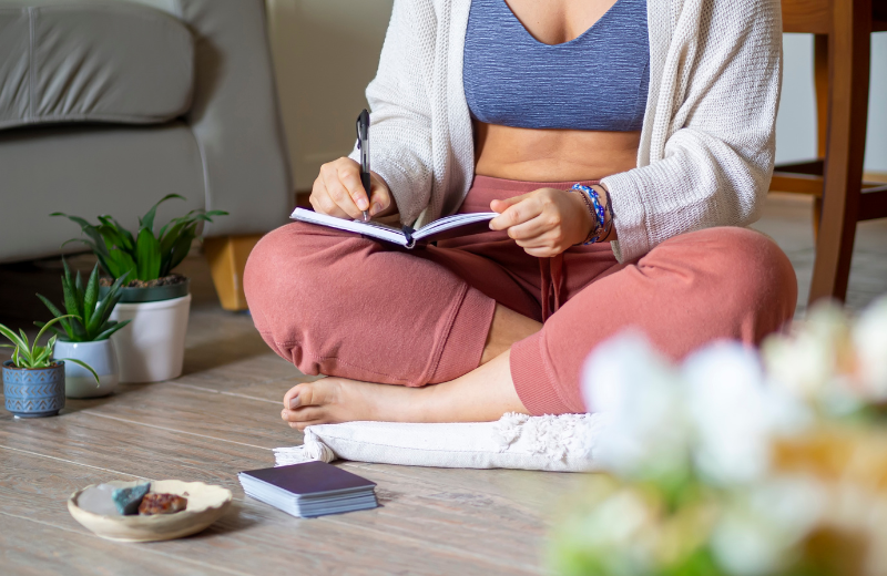 woman manifesting in journal sitting on floor