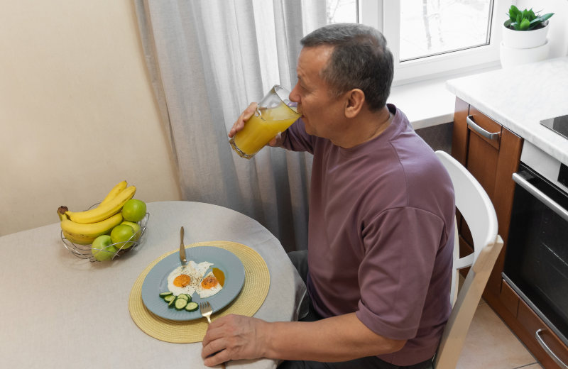 man with plate of food drinking orange juice