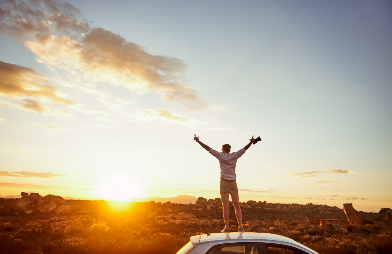 Image of someone cheering in the sunset.