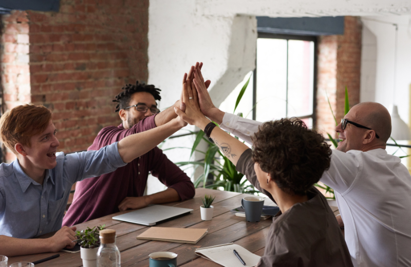 A group of people high fiving across the table.