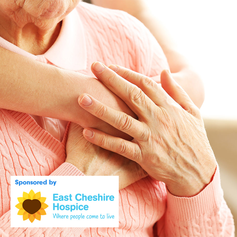 A hand hugs an elderly lady from behind, the elderly lady put her hand over the other persons hand in appreciation