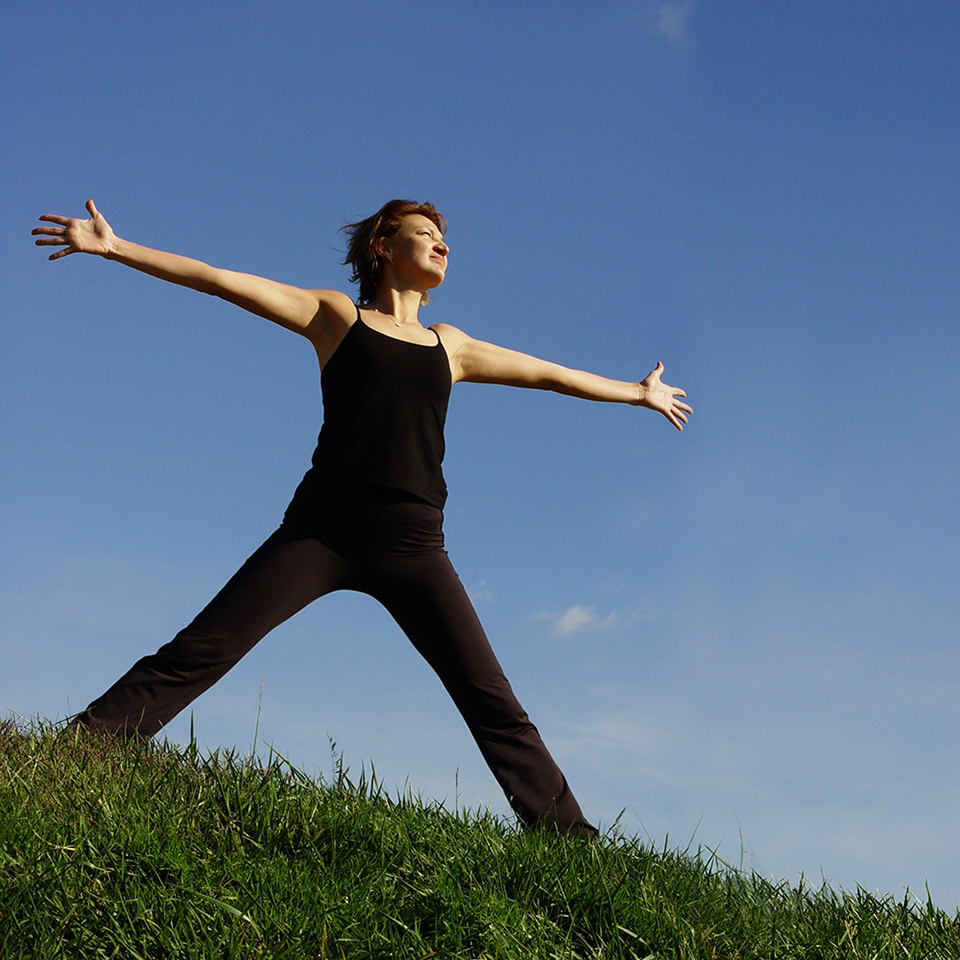 Woman on to of a hill with arms stretched out wide.